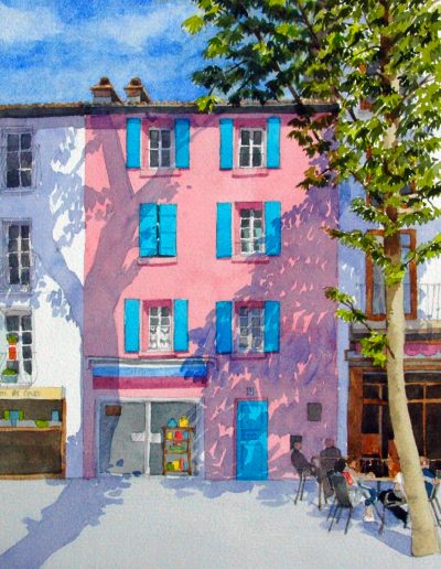 A watercolour painting of bright blue shutters on a pink building in Ceret, France. Outside there are people sat at a table and a tall leafy tree.